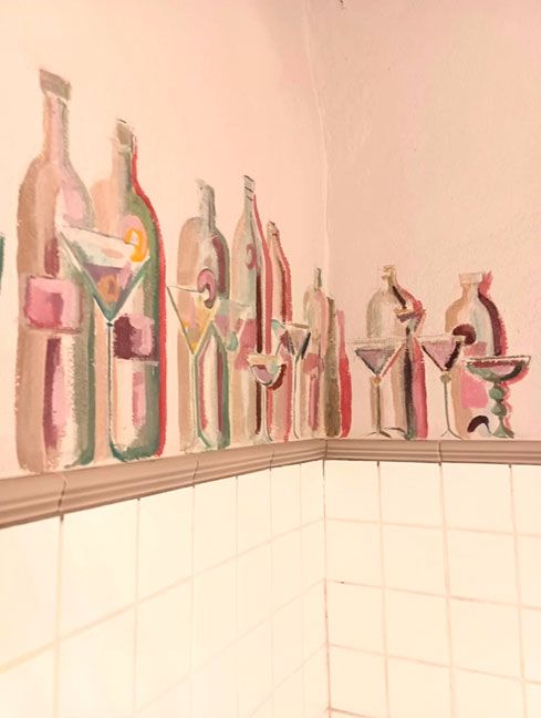 Mural con dibujos de botellas en pared de interior de local