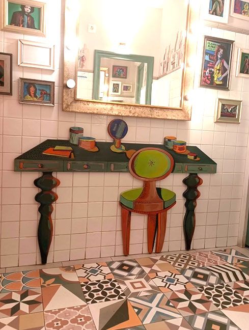 Interior con pared de azulejo blanco con espejo y trampantojo de mobiliario